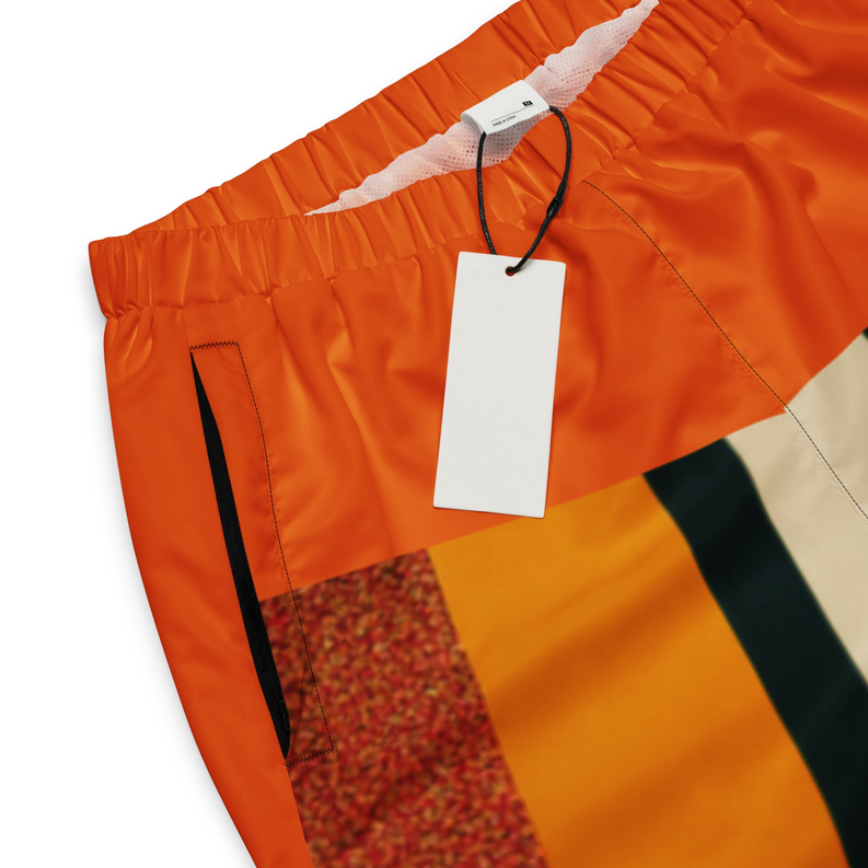 Orange track pants close-up with elastic waistband and black vertical stripe print
