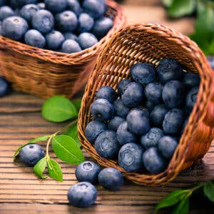 Blueberry dark balsamic vinegar shown with blueberries in a woven basket on wood