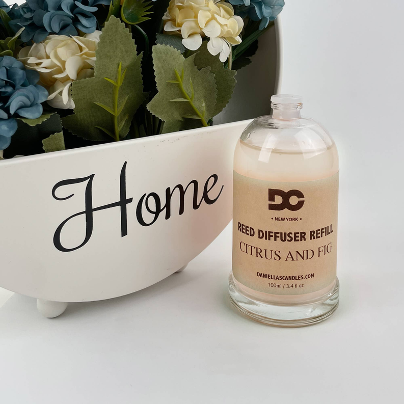 Reed diffuser refill oil bottle beside white planter, clear glass, 3.4 oz/100 mL
