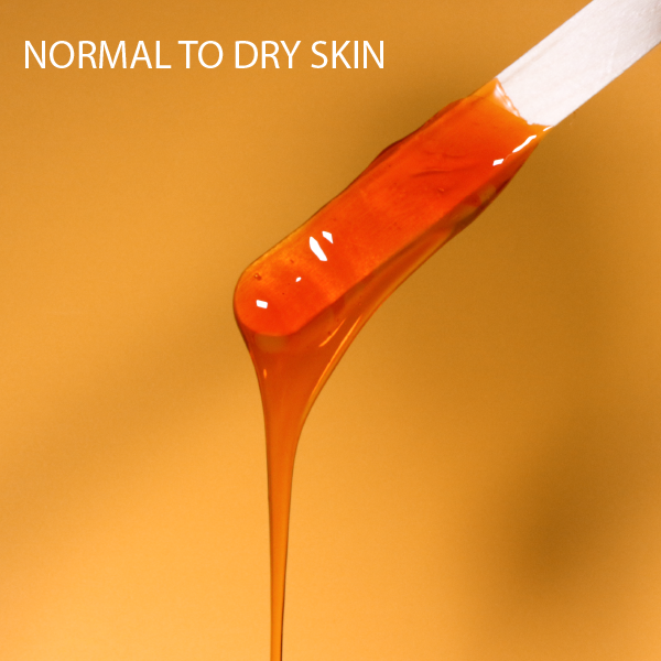 Orange amber hard wax ribbon on a spatula, ready for strip-free application