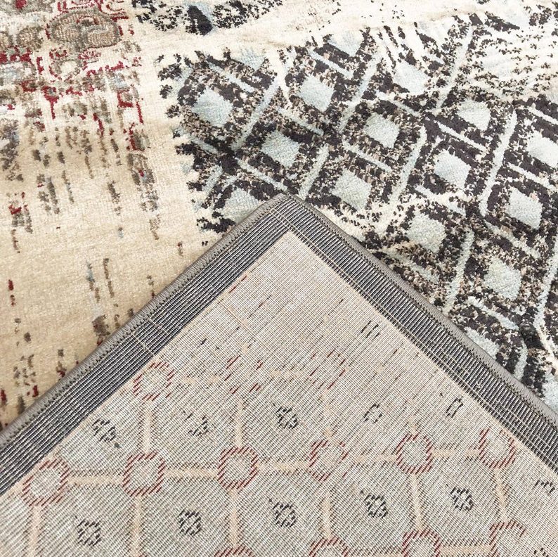 Beige ivory rug corner with black geometric motifs and lightly textured patterned pile