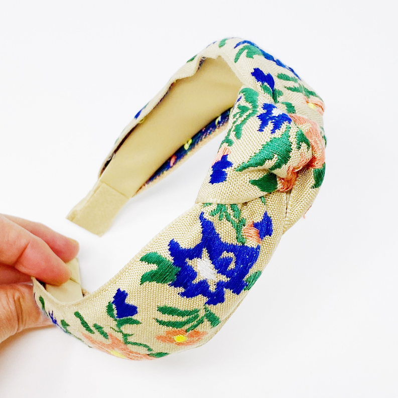 Woven floral headband with cream backing, blue and green leaves with orange accents