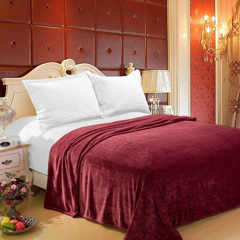 Plush burgundy throw blanket draped over bed, smooth velour-like surface