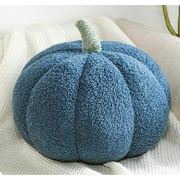 Blue boucle pumpkin pillow with green stem on a light cushion