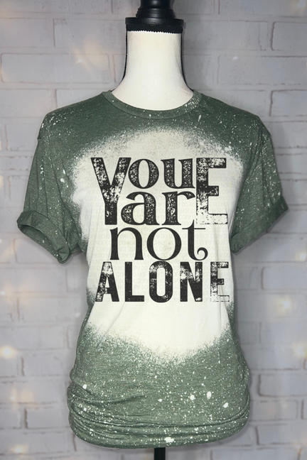 Green bleached graphic tee with black 'You are not alone' text on white center panel