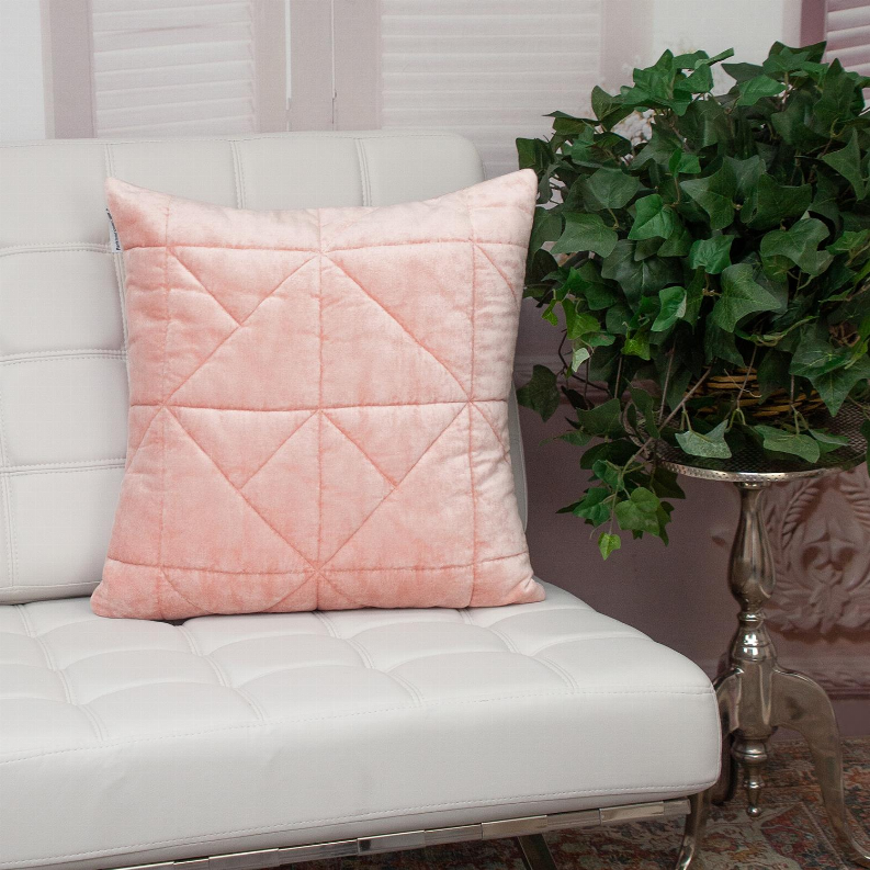 Pink quilted throw pillow on a white sofa cushion, diamond stitched pattern