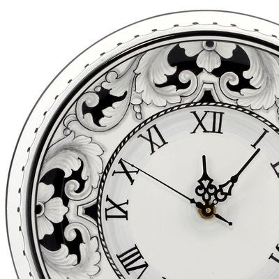 Ornate round wall clock close-up with black floral rim and Roman numerals