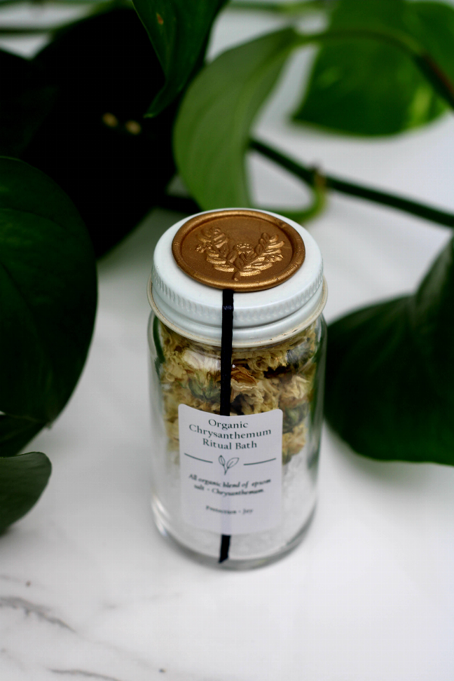 Organic bath salt jar close-up, dried flowers inside, white label and gold lid