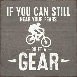 Wood sign with quote 'If you can still hear your fears' and 'Shift a gear' bicycle graphic