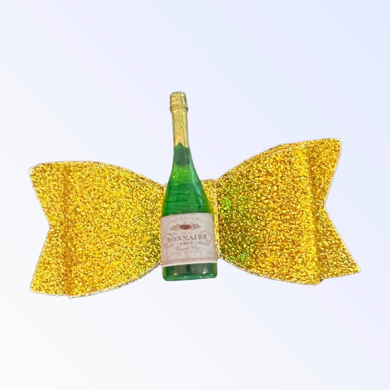 Close-up pair of yellow glitter dog hair bows with green bottle centerpiece