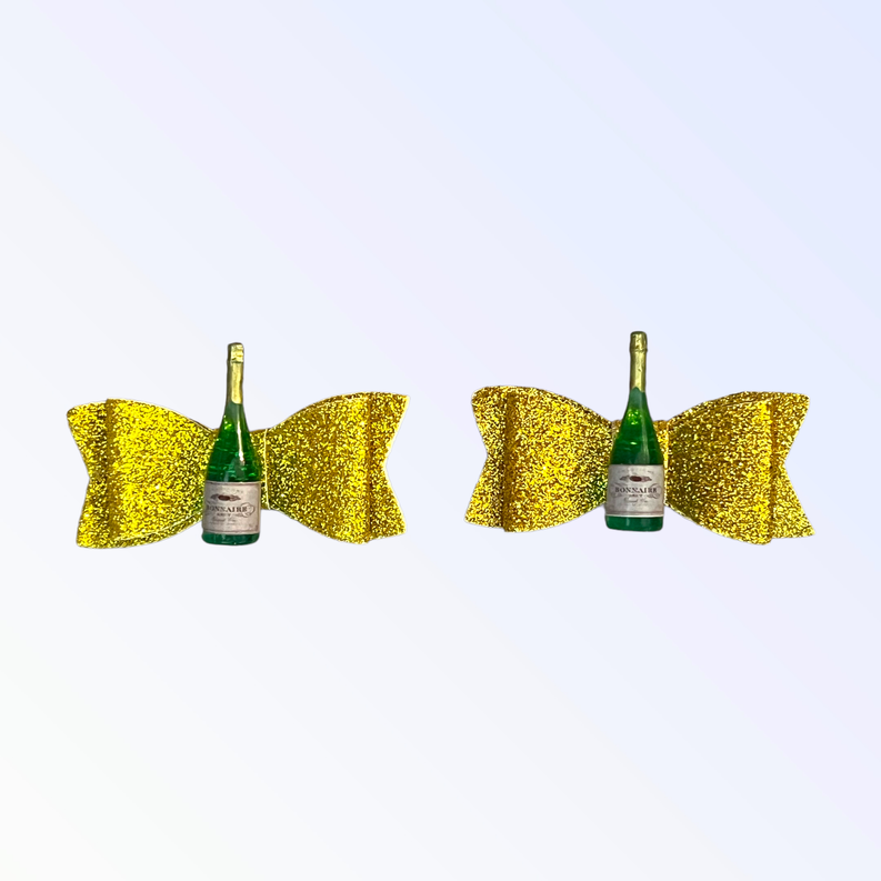 Two yellow glitter dog hair bows and small green bottle in between
