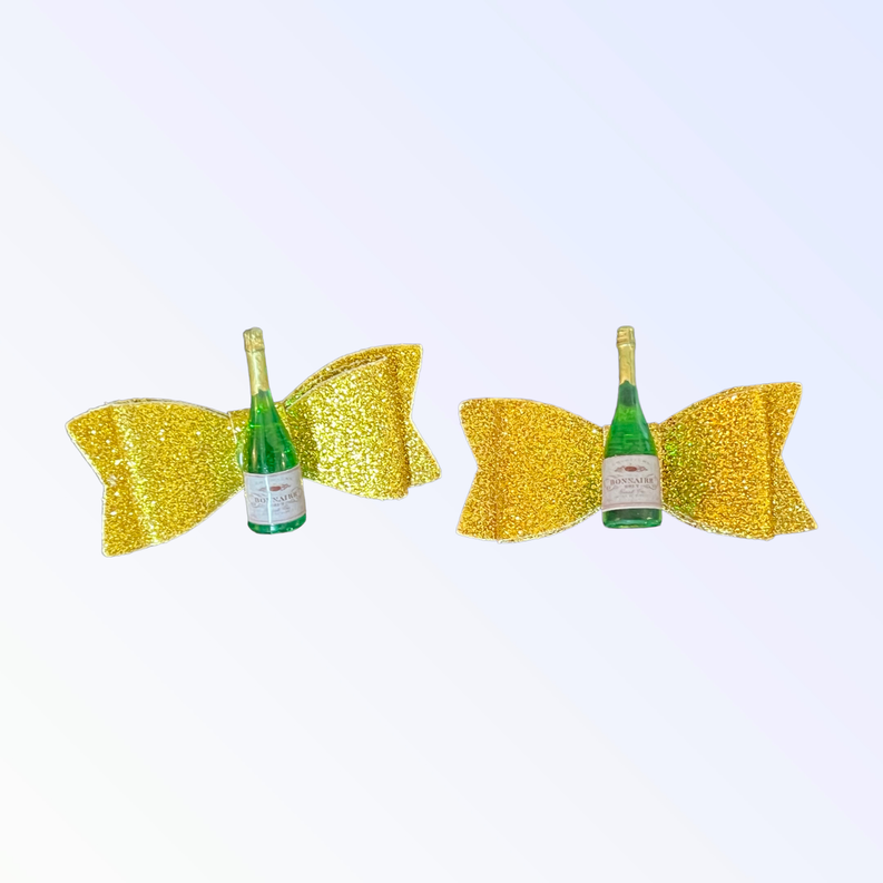Two yellow glitter dog hair bows with green bottle centered between