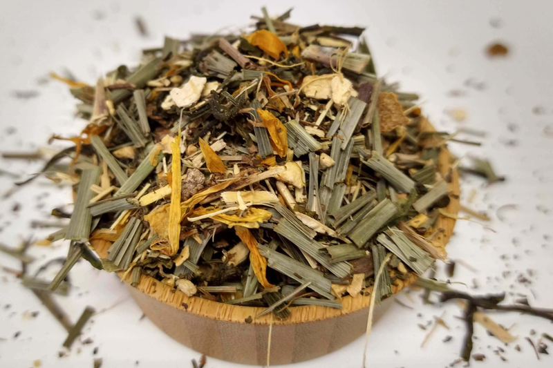Mixed dried lemon and ginseng herbal tea leaves in a round wooden bowl