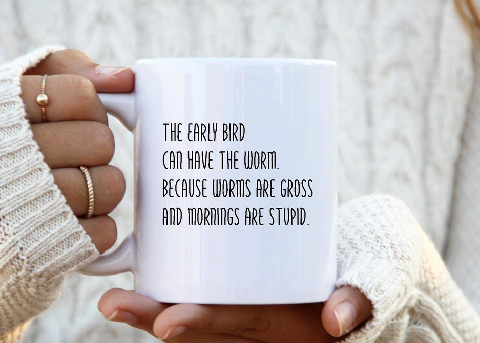 White ceramic coffee mug held in hands, with black quote text on front.