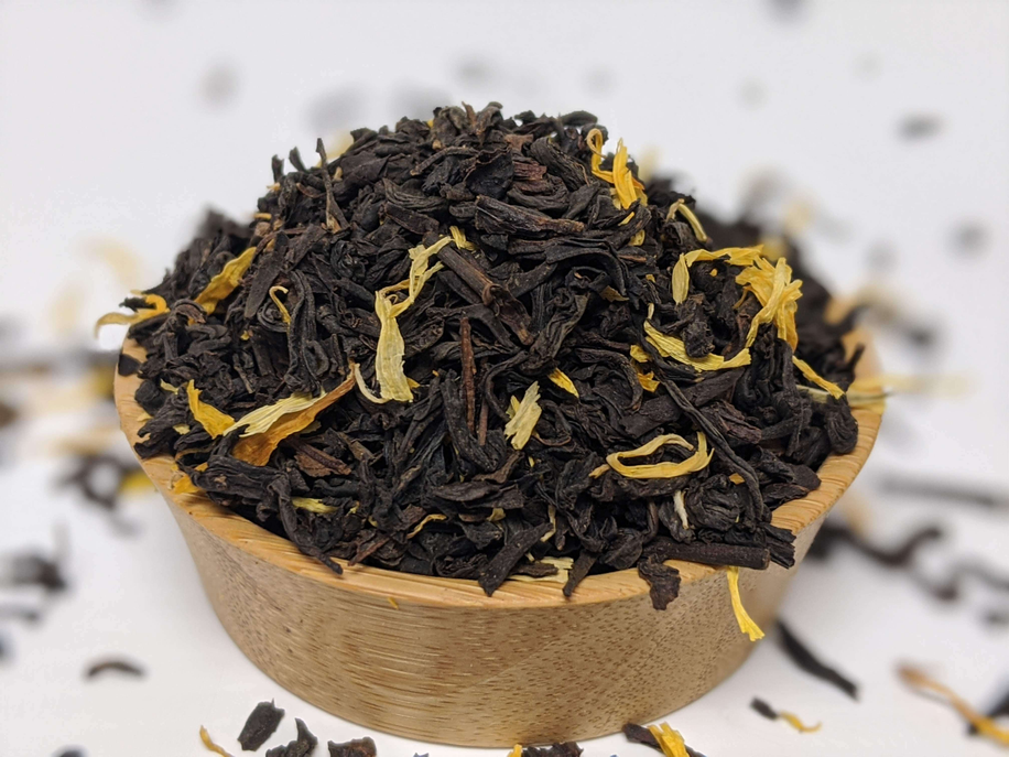 Loose mango-flavored black tea leaves in a wooden scoop