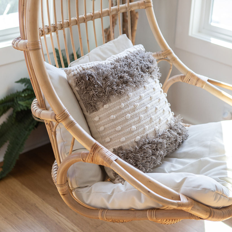 Textured throw pillow in light beige with gray shag fringe and dotted knit rows