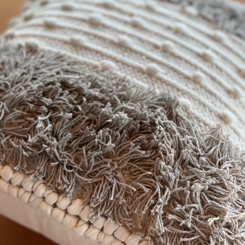 Close-up throw pillow fabric with braided shag fringe and raised dot knit pattern