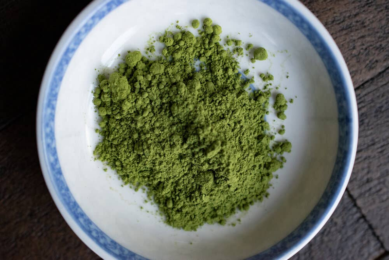 Green matcha powder heap in a white bowl