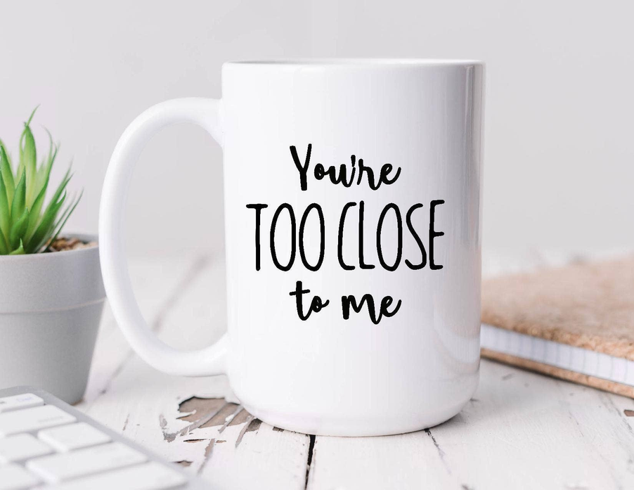 White coffee mug with bold 'You're too close to me' message on front
