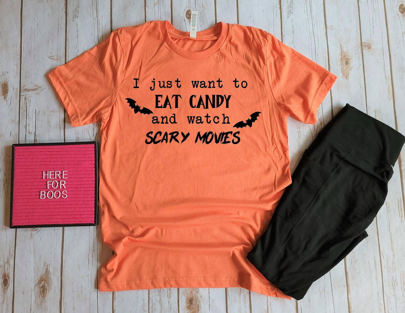 Orange crewneck T-shirt with black slogan: EAT CANDY, watch SCARY MOVIES