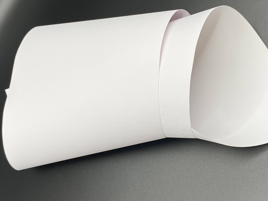 Roll of peel-and-stick vinyl wallpaper, plain white backer with curved edge