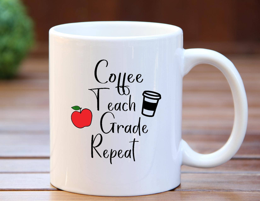 White ceramic coffee mug with 'Coffee Teach Grade Repeat' design on front, side view