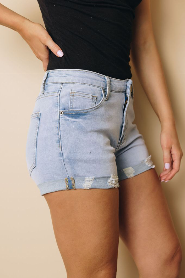 Light blue cuffed denim shorts side view with back pockets and ripped hem