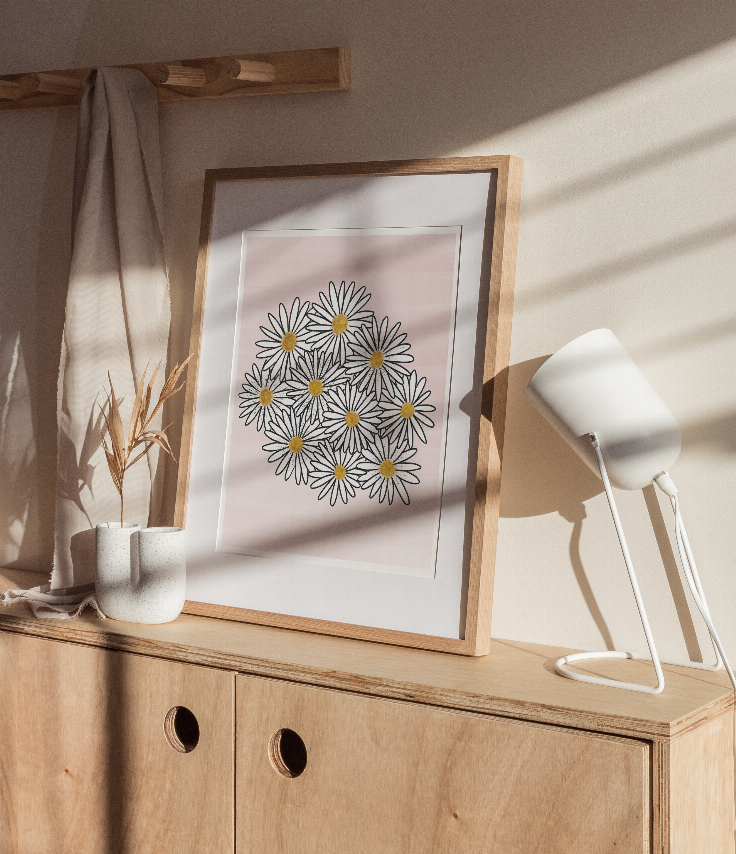 Framed daisy floral print with white border and black outlines, yellow centers on pink.