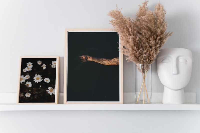 Light-framed daisy floral art print with white petals and yellow centers on dark background.