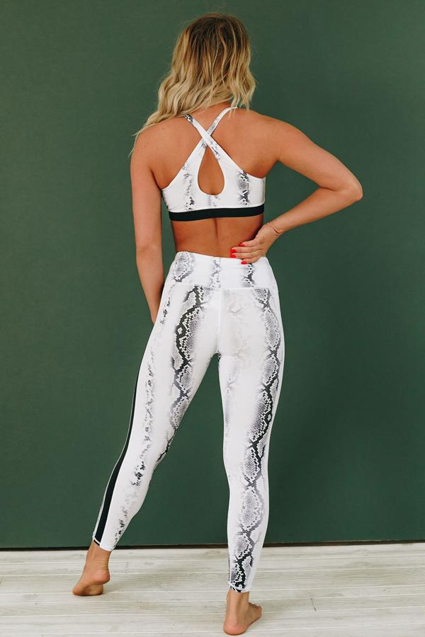 Snake-patterned active set, back view: crisscross sports bra straps with white leggings