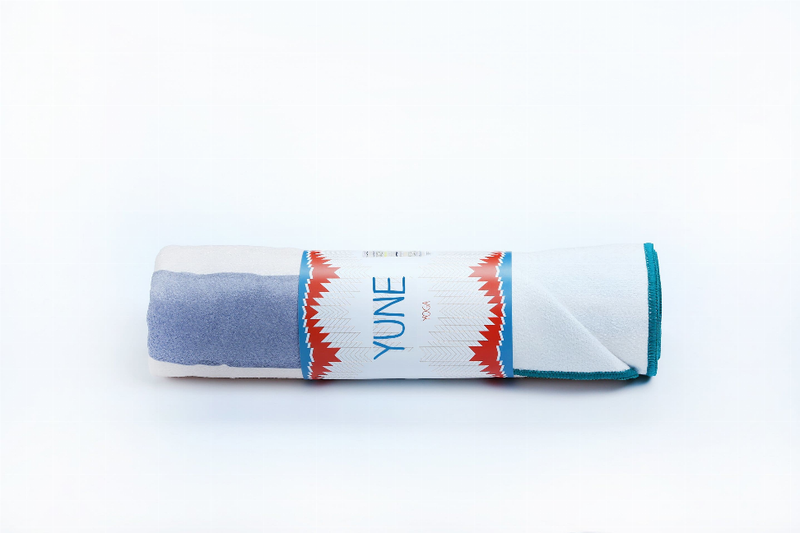 Rolled yoga towel with blue fabric, coral chevron band, turquoise edge and YUNE logo