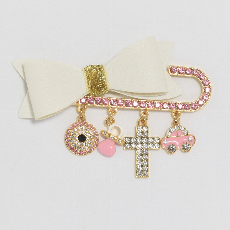 Beige bow baby pin with gold cross, eye, heart and car charms