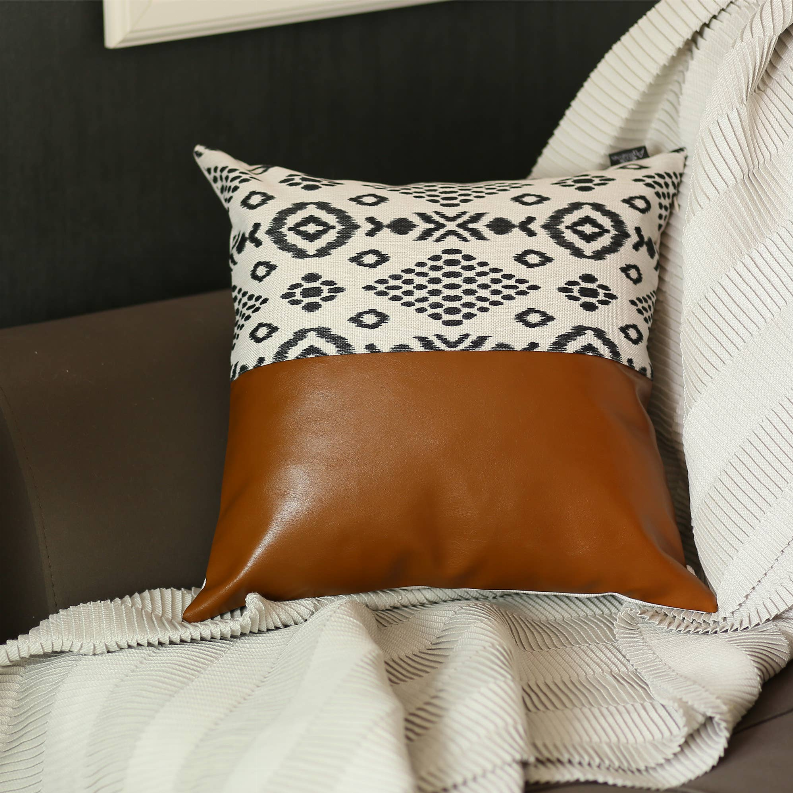 Faux leather throw pillow with brown base and black-and-white boho geometric top