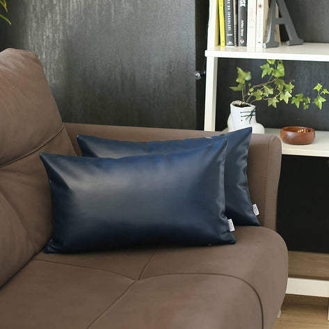 Two blue faux leather throw pillows on beige sofa, smooth sheen