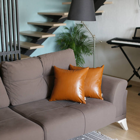 Square orange faux leather throw pillow with wrinkle-sheen finish on sofa
