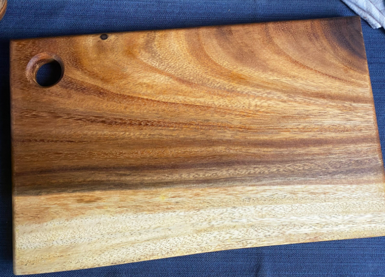 Live edge square wood board with round hanging hole, visible grain texture.