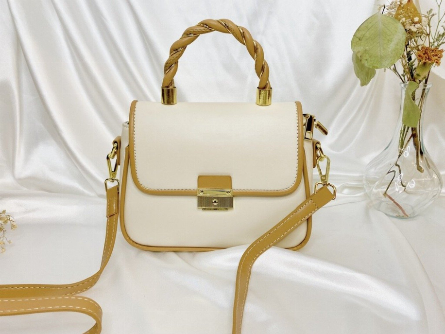 Cream small handbag with braided top handle, gold lock clasp, and crossbody strap.