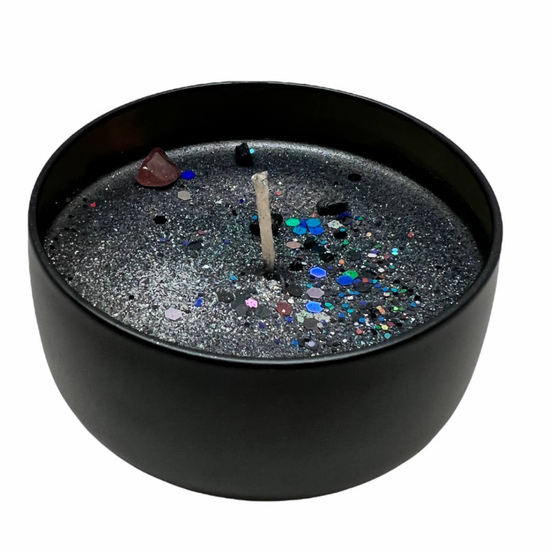 Black candle with glitter-filled wax bed, visible wick, in round matte tin