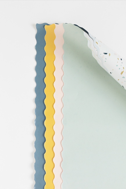 Two-sided gift wrap close-up: white terrazzo speckles with blue, pink, and green backing