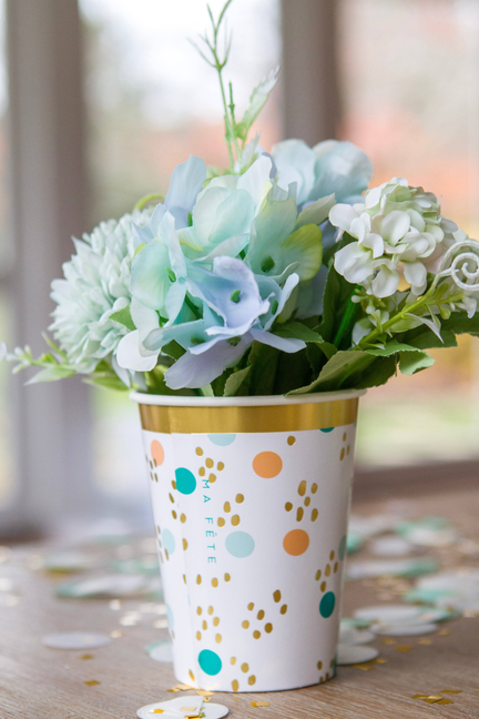 Fun fair cups with gold rim and colorful paw-print pattern, holding a bouquet