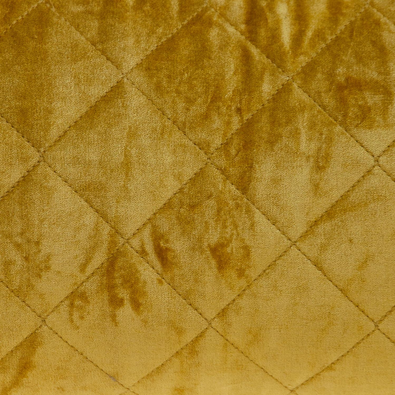 Gold diamond-stitched quilted pillow close-up on velour fabric