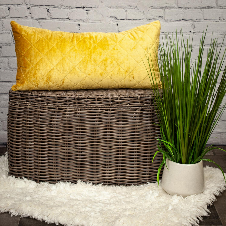 Gold quilted throw pillow with diamond stitching, shown on a woven basket stand