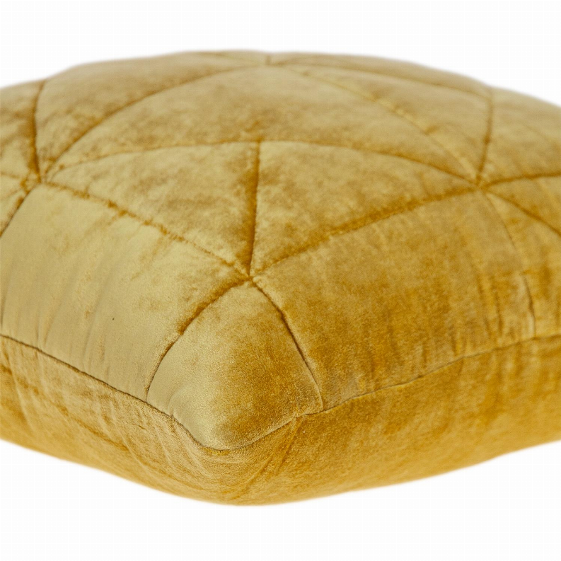 Close-up of mustard yellow quilted pillow showing stitched diamond panels and corner