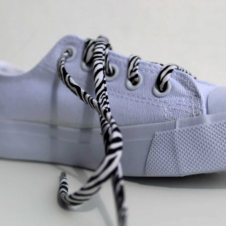 Zebra-print shoelaces on light gray canvas sneakers, black-and-white striped