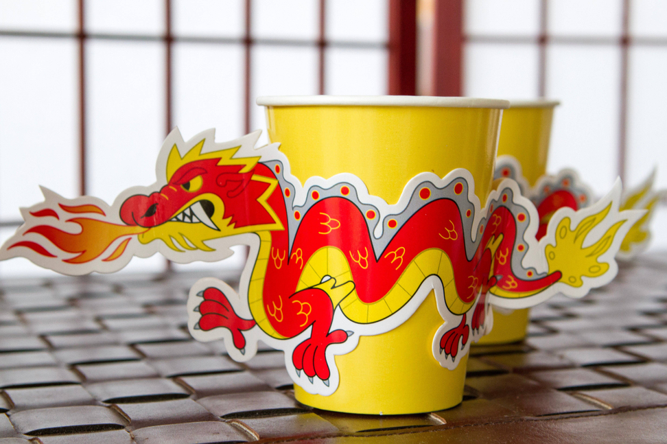 Yellow paper cup with red dragon graphics, plus another cup in back