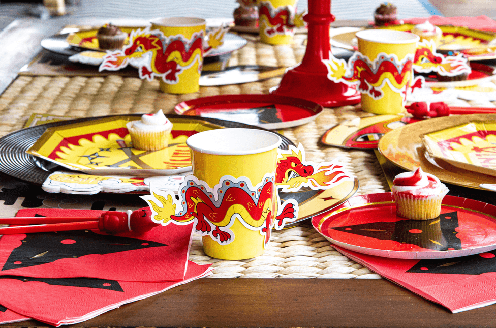 Dragon-themed party cups on table, yellow with red dragon graphics and white rims