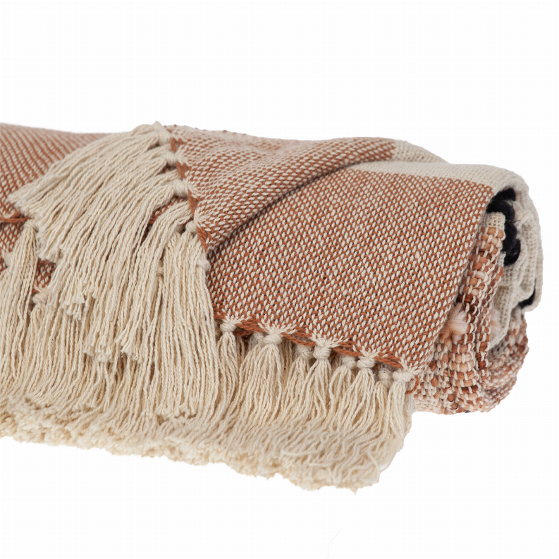 Close-up of woven throw blanket corner, cream and terracotta with long fringed trim