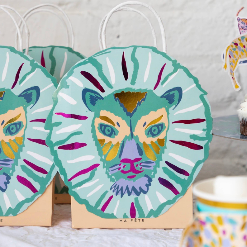 Set of lion face paper bags with green, pink, and teal illustration designs