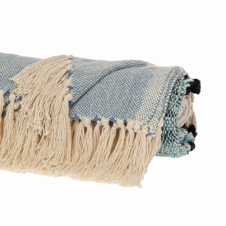 Cream and light-blue woven throw with fringe border and black pom-tassels on folded edge.