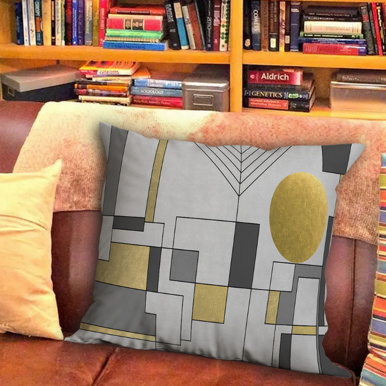 Decorative throw pillow in gray with gold accents and geometric blocks